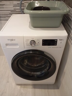 Un'unità lavatrice e asciugatrice Whirlpool con pannello di controllo, una lavatrice a carica frontale e un'asciugatrice a carica dall'alto.