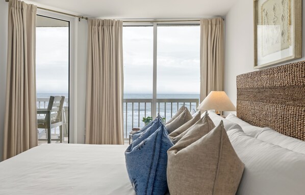Et hotelværelse med en seng, havudsigt, en balkon med stol og en lampe.