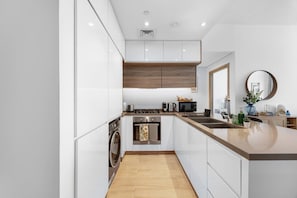 Eine moderne Küche mit weißen Schränken, einer Holz Arbeitsplatte, einem eingebauten Ofen, einer Mikrowelle und einem Spülbecken.