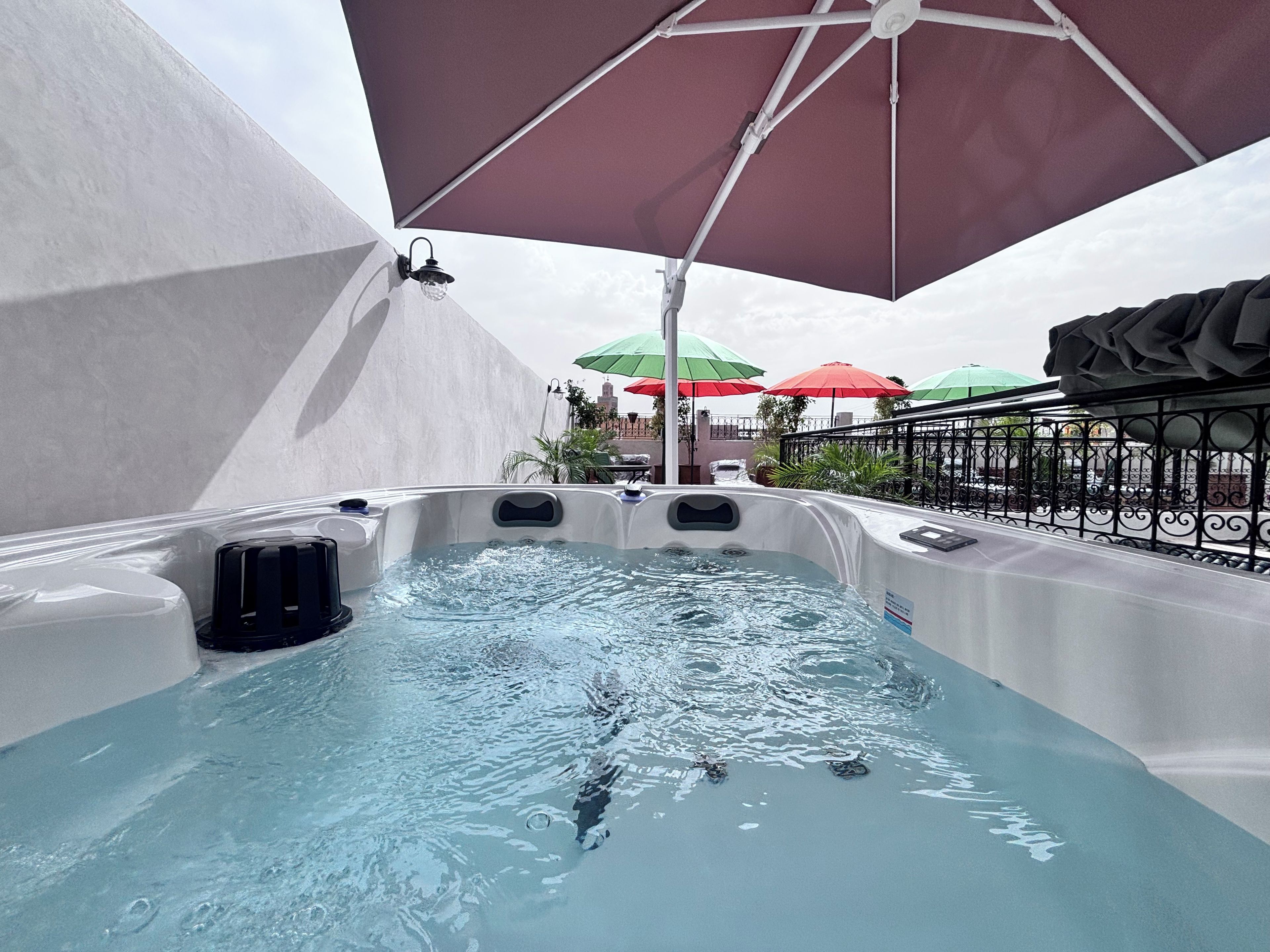 Ein Whirlpool mit Wasser, umgeben von Sonnenschirmen und einem Geländer.