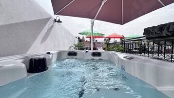 Ein Whirlpool mit Wasser, umgeben von Sonnenschirmen und einem Geländer.