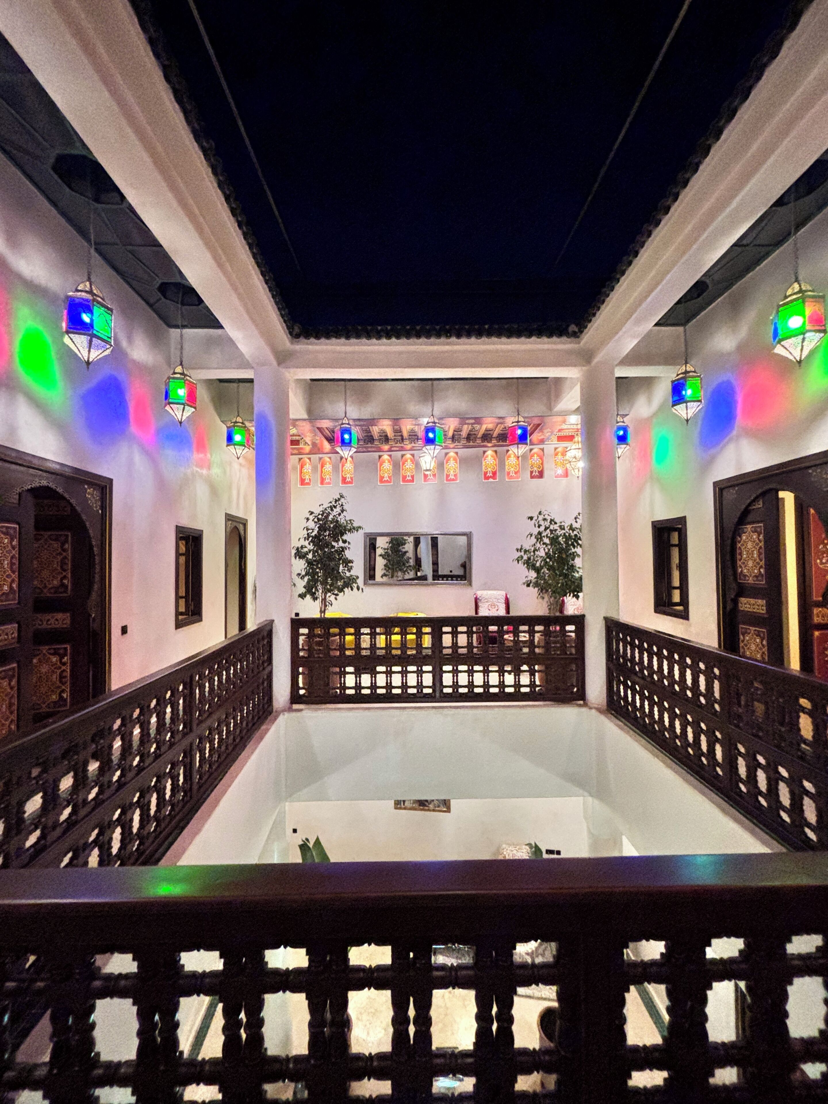 Un interior tradicional con un espacio central abierto, faroles decorativos y una barandilla estampada.
