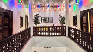 Un interior tradicional con un espacio central abierto, faroles decorativos y una barandilla estampada.