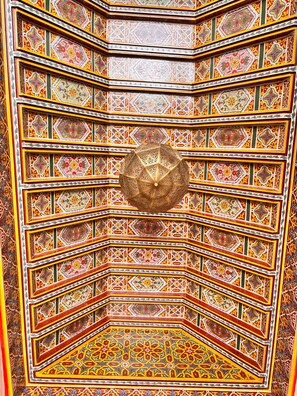 A detailed, multi-tiered ceiling with intricate geometric patterns and a central spherical light fixture.