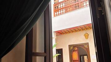 Una ventana abierta con vistas a un edificio tradicional con balcón y puertas ornamentadas.
