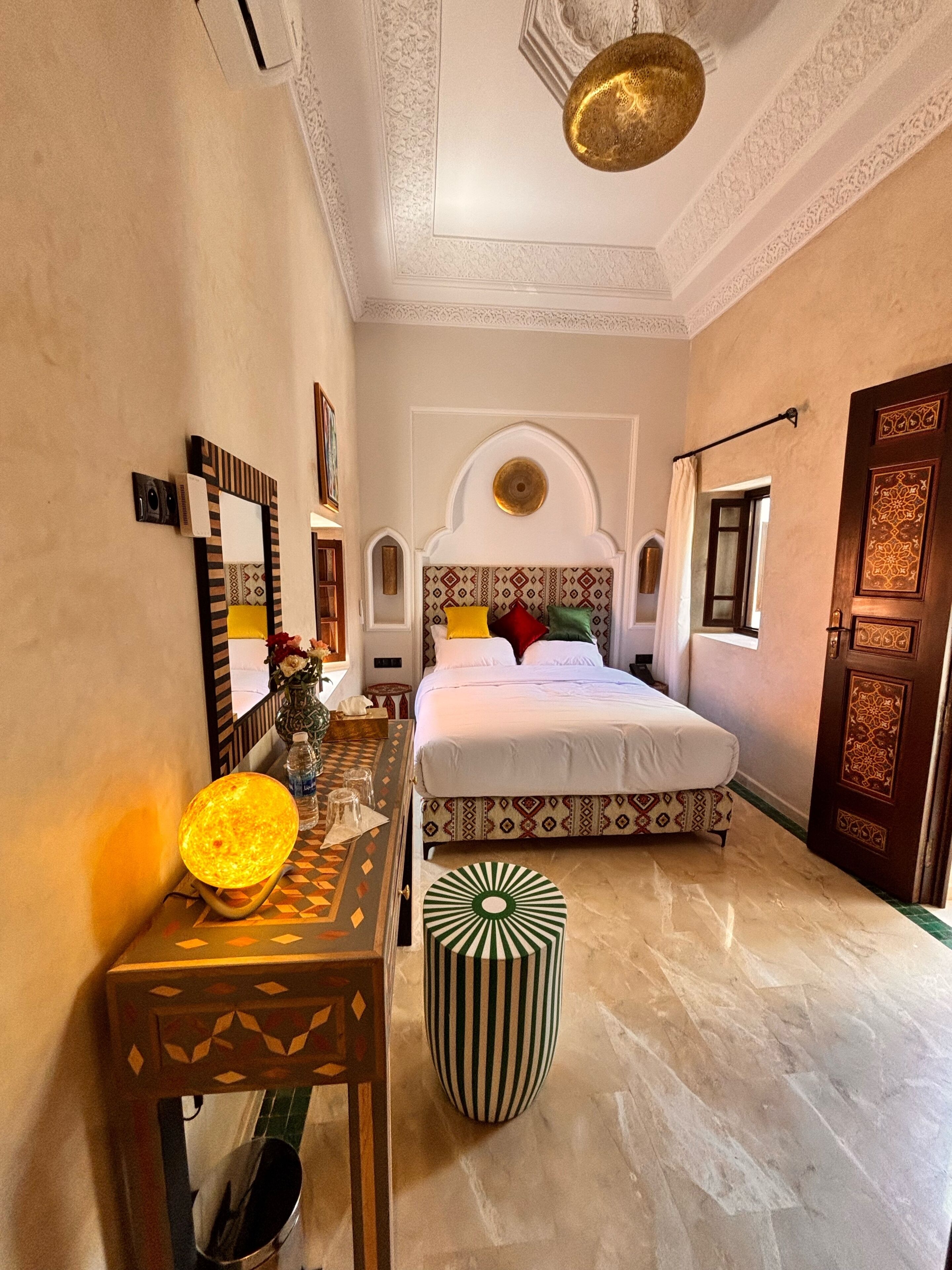 A bedroom with a bed, a desk, a chair, and a decorative wall.