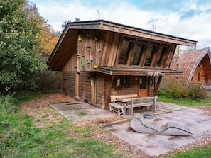 Eine Holzhütte mit geneigtem Dach, einer Holzterrasse und einer Bank.