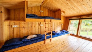 Eine Holzhütte mit Etagenbetten, einem Fenster und Holzboden.