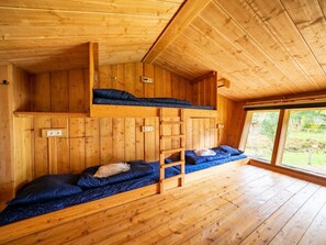 Eine Holzhütte mit Etagenbetten, einem Fenster und Holzboden.