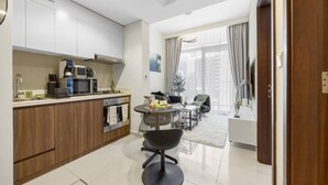Una cucina moderna con elettrodomestici integrati, una zona pranzo con tavolo e sedie rotonde e un soggiorno con divano e televisore.