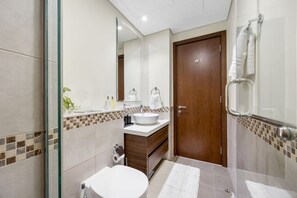Ein modernes Badezimmer mit einer Duschkabine aus Glas, einem weißen Waschbecken und einer Holztür.