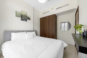 Ein Schlafzimmer mit Bett, Schrank, Spiegel und einer Pflanze.