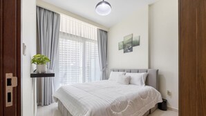 Una camera da letto con un letto, tende, una pianta in vaso e un'opera d'arte appesa al muro.