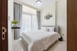 A bedroom with a bed, curtains, a potted plant, and artwork on the wall. - Luxury 1BR, Business Bay, Burj Khalifa Peek View (Dubai)
