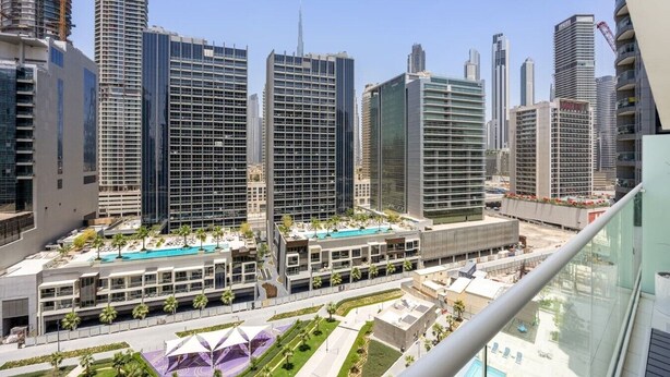 Un moderno grattacielo con area piscina e vista su altri edifici alti.
