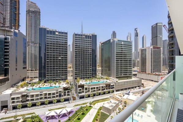 A modern high-rise building with a pool area and a view of other tall buildings. - Luxury 1BR, Business Bay, Burj Khalifa Peek View (Dubai)
