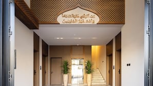 A hotel lobby with a marble floor, wooden doors, and a decorative ceiling.