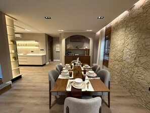 A modern dining area with a wooden table set for six, surrounded by grey chairs. - Atrah Luminous 3BR Luxury Family Residence (Madinah)