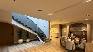 A modern interior with a staircase, dining area, and kitchen.