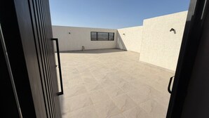 An open terrace with a tiled floor, a window, and a door. - Atrah Luminous 3BR Luxury Family Residence (Madinah)