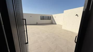 Une terrasse ouverte avec un sol carrelé, une fenêtre et une porte.