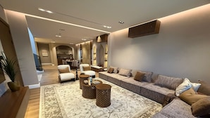 A modern living room with a sectional sofa, armchairs, a coffee table, and a patterned rug.