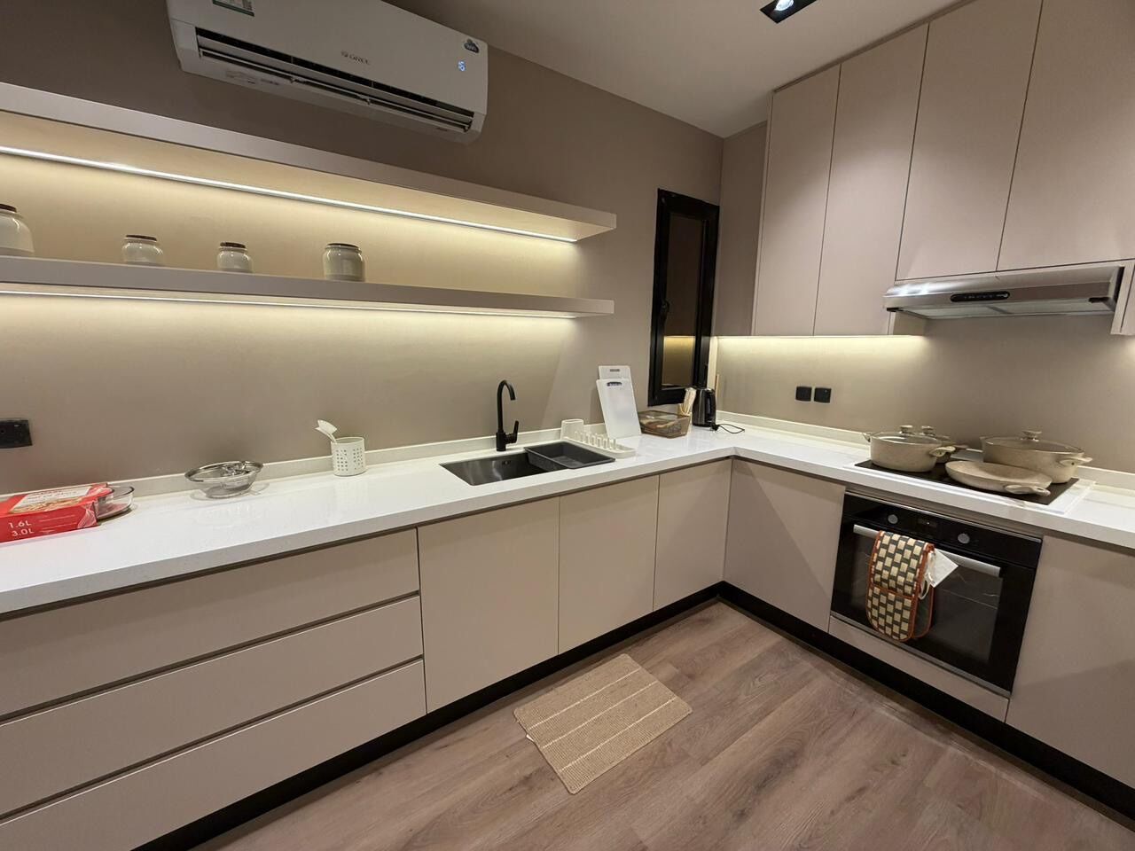 A modern kitchen with a built-in oven, a sink, and a countertop with jars and a kettle.