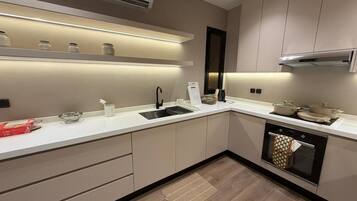 A modern kitchen with a built-in oven, a sink, and a countertop with jars and a kettle.
