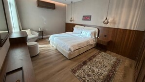 Ein Schlafzimmer mit einem Bett, Nachttischen, einem Spiegel, einem Fenster und einem gemusterten Teppich.