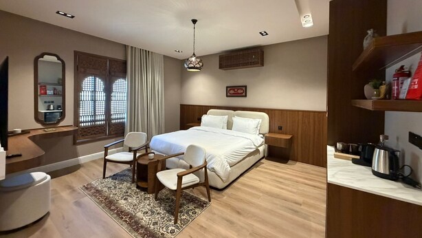 Una habitación de hotel moderna con una cama grande, un escritorio, una silla, un televisor y una cafetera.