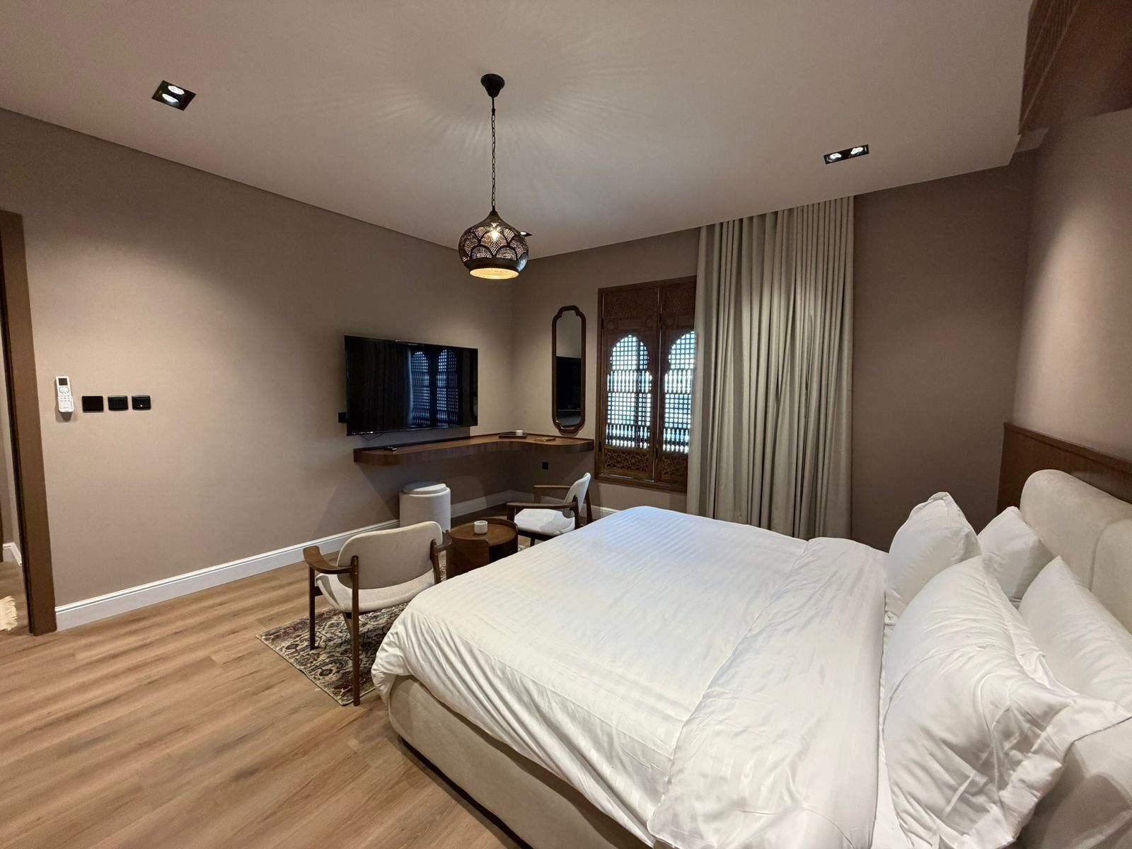 Une chambre d’hôtel équipée d’un lit, d’un bureau, d’une chaise, d’une télévision et d’une fenêtre avec des rideaux.