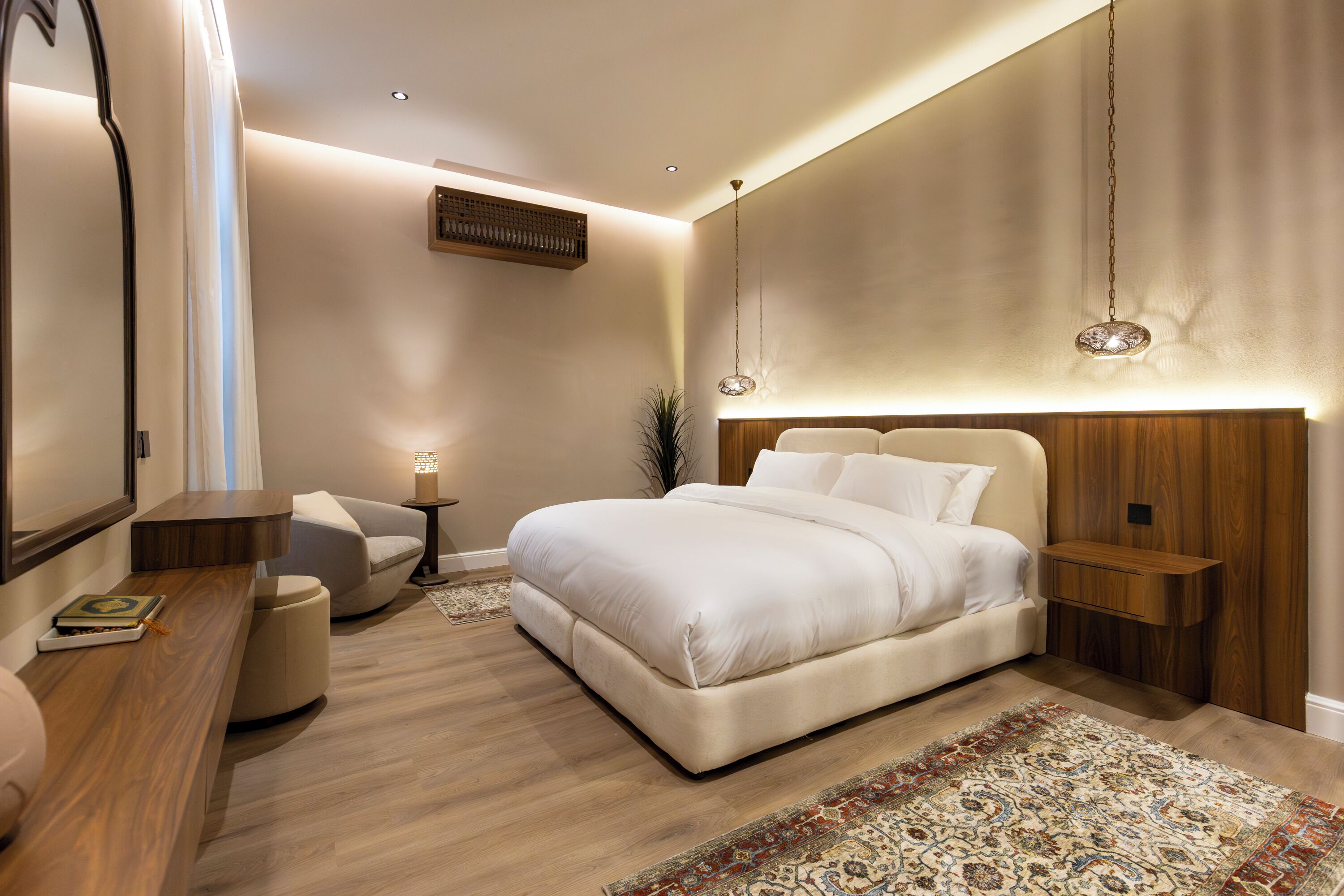 Un dormitorio moderno con una cama grande, mesitas de noche, un sillón y una alfombra decorativa.