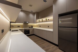 A modern kitchen with a stainless steel refrigerator, a built-in oven, and a dishwasher. - Atrah Elegant 3BR Apartment With Maid's Room (Madinah)