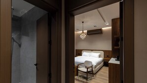 Une chambre à coucher moderne avec un grand lit, une table de chevet en bois, un bureau et un luminaire suspendu.
