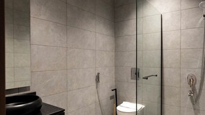 Une salle de bain moderne avec une douche à parois de verre, un lavabo noir et des toilettes.
