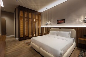 A bedroom with a large bed, a wooden partition, a wall-mounted light fixture, and a small bedside table. - Atrah Spacious 3BR Family Stay + Maid's Room (Madinah)