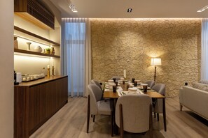 A dining area with a wooden table, chairs, and a stone wall.