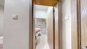 Ein Flur, der zu einem Badezimmer mit Waschbecken und Dusche führt.