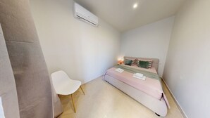 Ein Schlafzimmer mit einem Bett, einem Sessel, einer Klimaanlage und einer Nachttischlampe.