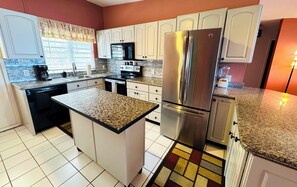 A kitchen with white cabinets, a stainless steel refrigerator, a microwave, and a coffee maker. - Brand New to VRBO-New Booking Discount-Gorgeous Sea Views, Generator, Wifi, Pool (Christiansted)