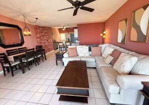 A living room with a sofa, a coffee table, and a dining area with chairs and a table. - The Pink Turtle-New Booking Discount-Gorgeous Sea Views, Generator, Wifi, Pool (Christiansted)