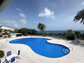 A pool with lounge chairs, a view of the ocean, and palm trees. - Brand New to VRBO-New Booking Discount-Gorgeous Sea Views, Generator, Wifi, Pool (Christiansted)