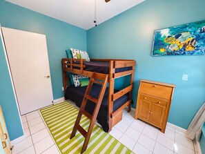 A room with a bunk bed, a small wooden cabinet, and a striped rug. - The Pink Turtle-New Booking Discount-Gorgeous Sea Views, Generator, Wifi, Pool (Christiansted)