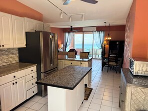 A kitchen with a refrigerator, a dining area with chairs, and a view of the ocean. - Brand New to VRBO-New Booking Discount-Gorgeous Sea Views, Generator, Wifi, Pool (Christiansted)