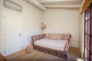 Ein Zimmer mit einem Bett, einer Lampe, einer Tür und einem Fenster.