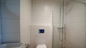 Ein modernes Badezimmer mit einer Duschkabine, einer Toilette und einer Badewanne.