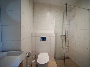 A modern bathroom with a glass-enclosed shower, a toilet, and a bathtub. - Water-view Holiday Home in Kampen (Kampen)