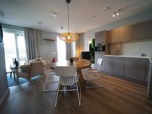A modern kitchen with a dining area, wooden flooring, and a large window. - Water-view Holiday Home in Kampen (Kampen)