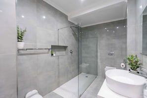 A modern bathroom with a glass shower enclosure, a freestanding bathtub, and a toilet.
