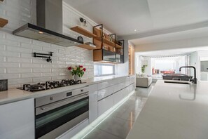 Une cuisine moderne avec des carreaux de métro blancs, un four encastré et une hotte de cuisson en acier inoxydable.